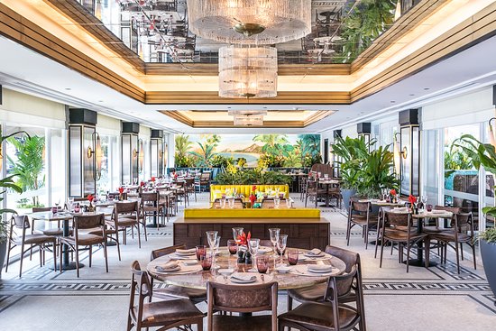 A nook of the restaurant with emerald green booth seating and a beautiful view of the sky outside