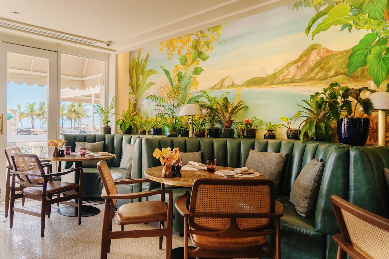 A picture of the naturally lit wide space of the restaurant with brightly colored, tasteful decor and shining chandeliers hanging from the ceiling